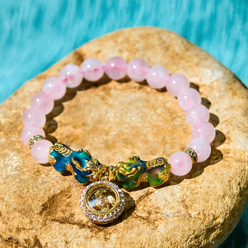 Pink crystal bracelet with double PiXiu on stone by turquoise water