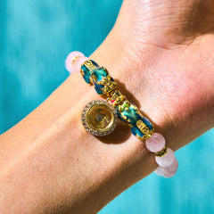 Pink crystal bracelet worn on wrist against turquoise blue background