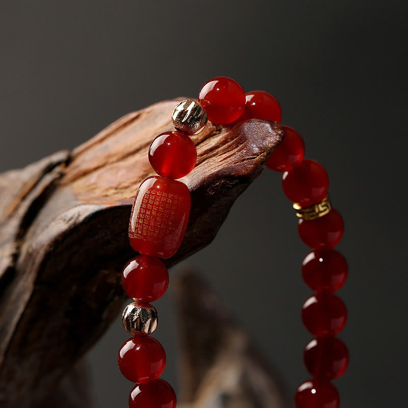 Red Green Agate Buddhist Sutras Calm Bracelet – draped over natural driftwood, macro close-up of gold sutra bead detail, grou