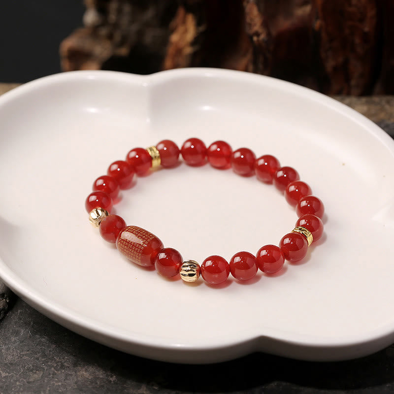Red Green Agate Buddhist Sutras Calm Bracelet – arranged on white ceramic dish, three-quarter view with dark organic backgrou