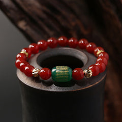 Red Green Agate Buddhist Sutras Calm Bracelet – red 8mm beads with gold-inscribed green sutra barrel bead on dark ceramic ves
