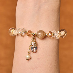 Citrine PiXiu Bracelet – Bracelet worn on wrist showing golden PiXiu with citrine beads and pearl charm, warm wood background