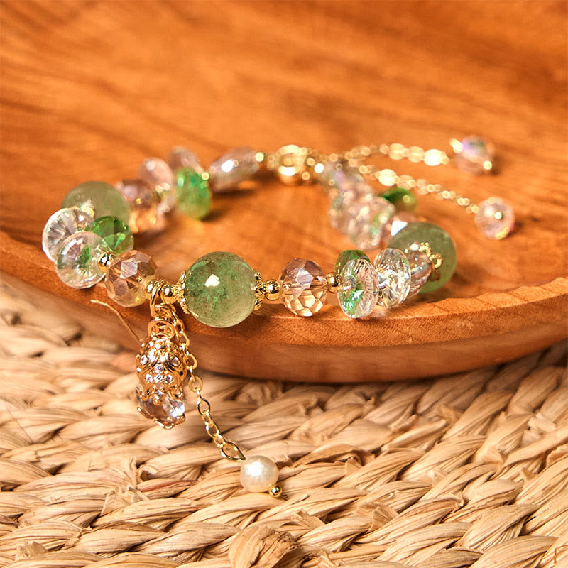 Green Strawberry Quartz Bracelet – Green quartz bracelet with golden PiXiu on wooden plate and woven straw mat