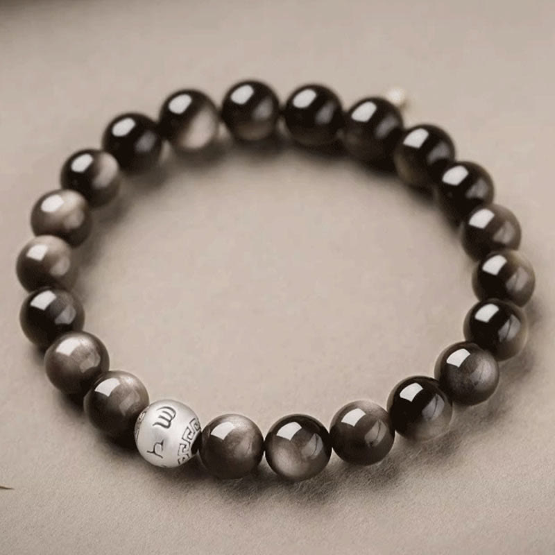 Silver Sheen Obsidian Bracelet – top down circular arrangement on beige fabric with engraved silver bead, grounding