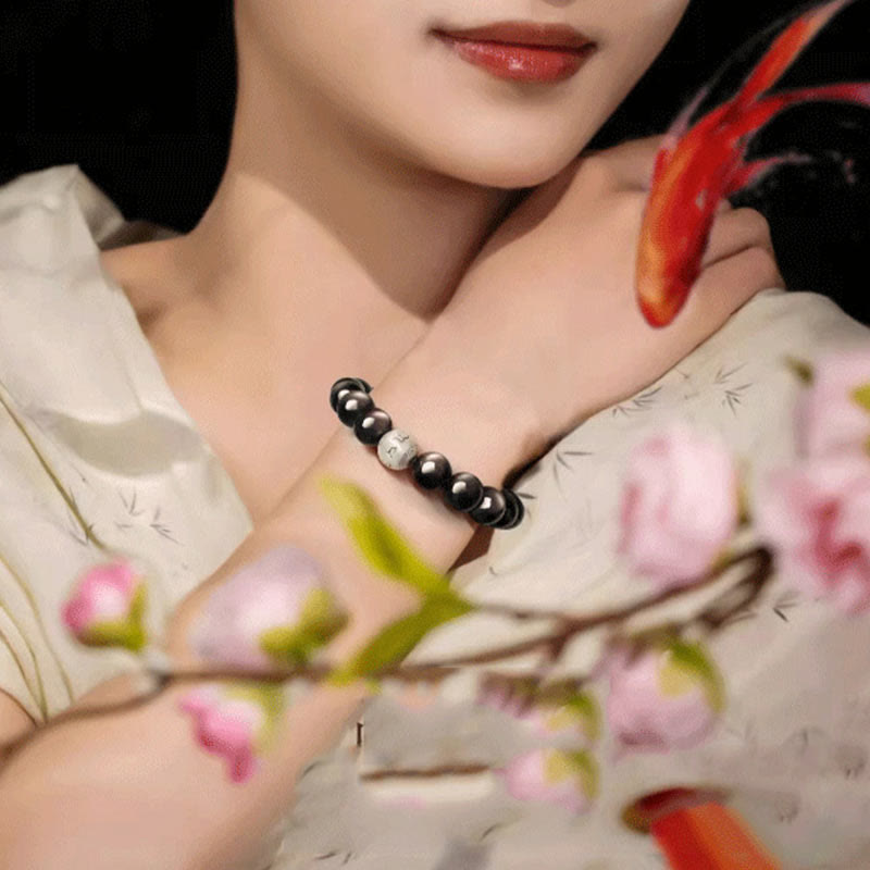 Silver Sheen Obsidian Bracelet – worn near cherry blossoms and koi fish motif in zen setting, grounding protection