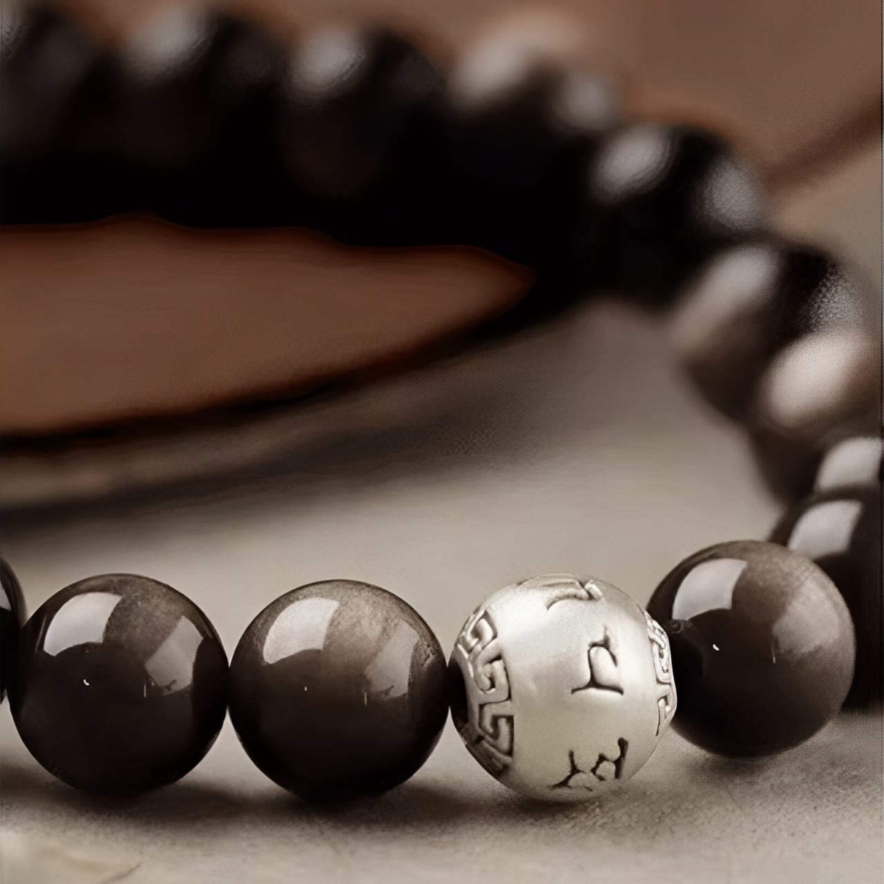 Silver Sheen Obsidian Bracelet – close up S curve showing engraved silver accent bead with Greek key pattern, grounding
