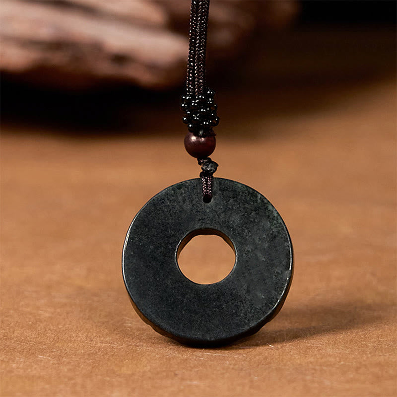 Back view of black-green jade pendant on warm brown background