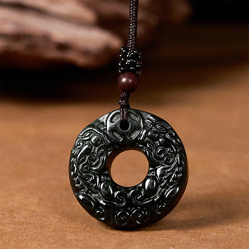 Black-green jade pendant angled view against brown wood backdrop