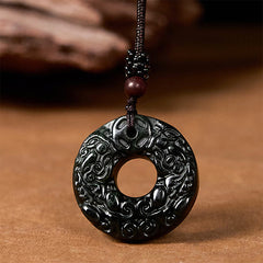 Black-green jade pendant angled view against brown wood backdrop