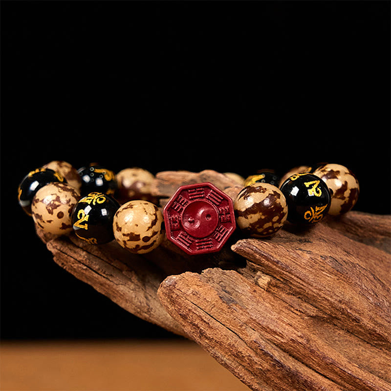 Bodhi Seed Bagua Yin Yang Bracelet – Low angle on dark wood, glossy beads with Sanskrit gold text