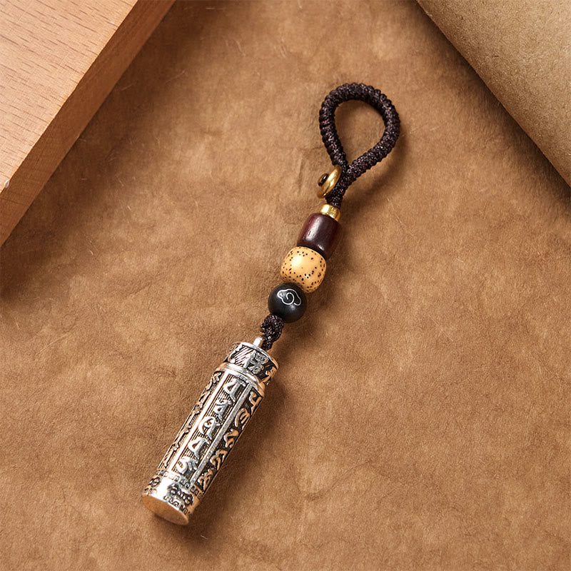 Tibetan Copper Vajra Key Chain – diagonal view on kraft paper with mantra cylinder and bead cord, protection Main image