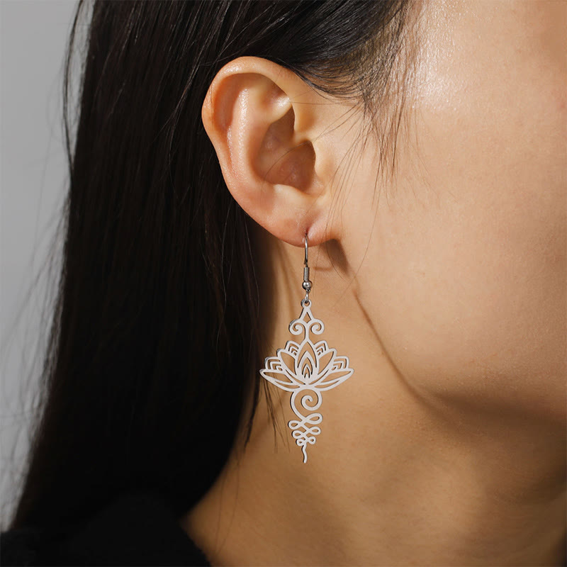 Hollow Lotus Stainless Steel Enlightenment Drop Earrings - worn on ear profile, neutral gray bg, delicate filigree lotus