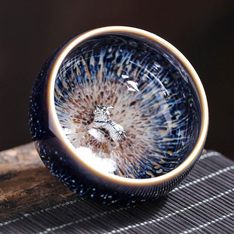 Jianzhan 12 Cup Set - cup with silver phoenix, iridescent blue glaze, three-quarter angle