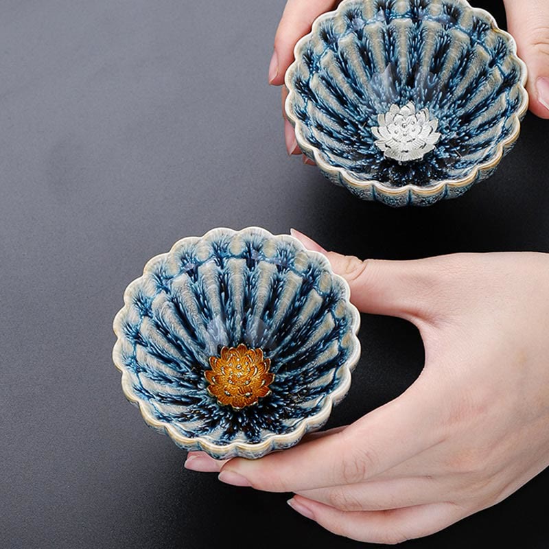 Two Jianzhan Lotus Ceramic Tea Cups held in hands showing gold and silver lotus centers