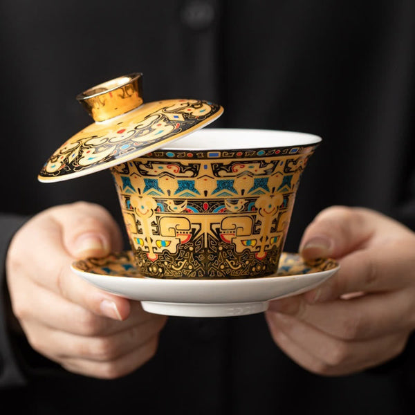 Dunhuang Ceramic Gaiwan Tea Set – Gold-ground gaiwan held in hands on black, taotie and cloud, Royal Display