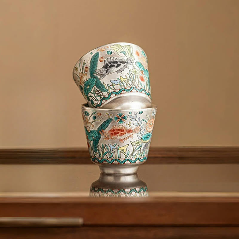 Fish Lotus Tea Cup – stacked pair showing silver interior and koi lotus exterior, wood surface, ceramic teacup
