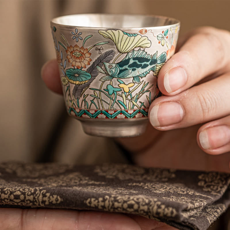 Fish Lotus Tea Cup – fingers gripping cup revealing koi scales and aquatic plants, ceramic teacup