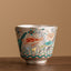 Fish Lotus Tea Cup – silver metallic body with koi and lotus enamel, studio side view, artisan teacup