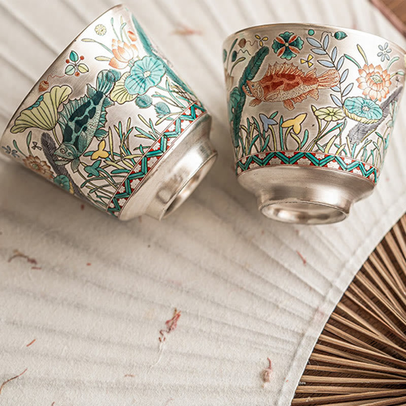 Fish Lotus Tea Cup – twin cups tilted on woven linen revealing full enamel fish artwork, ceramic teacup