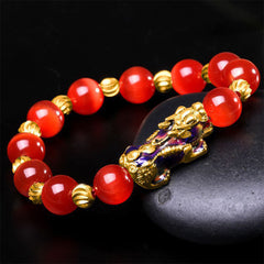 Red cat's eye beads with gold spacers and enamel PiXiu on black stone