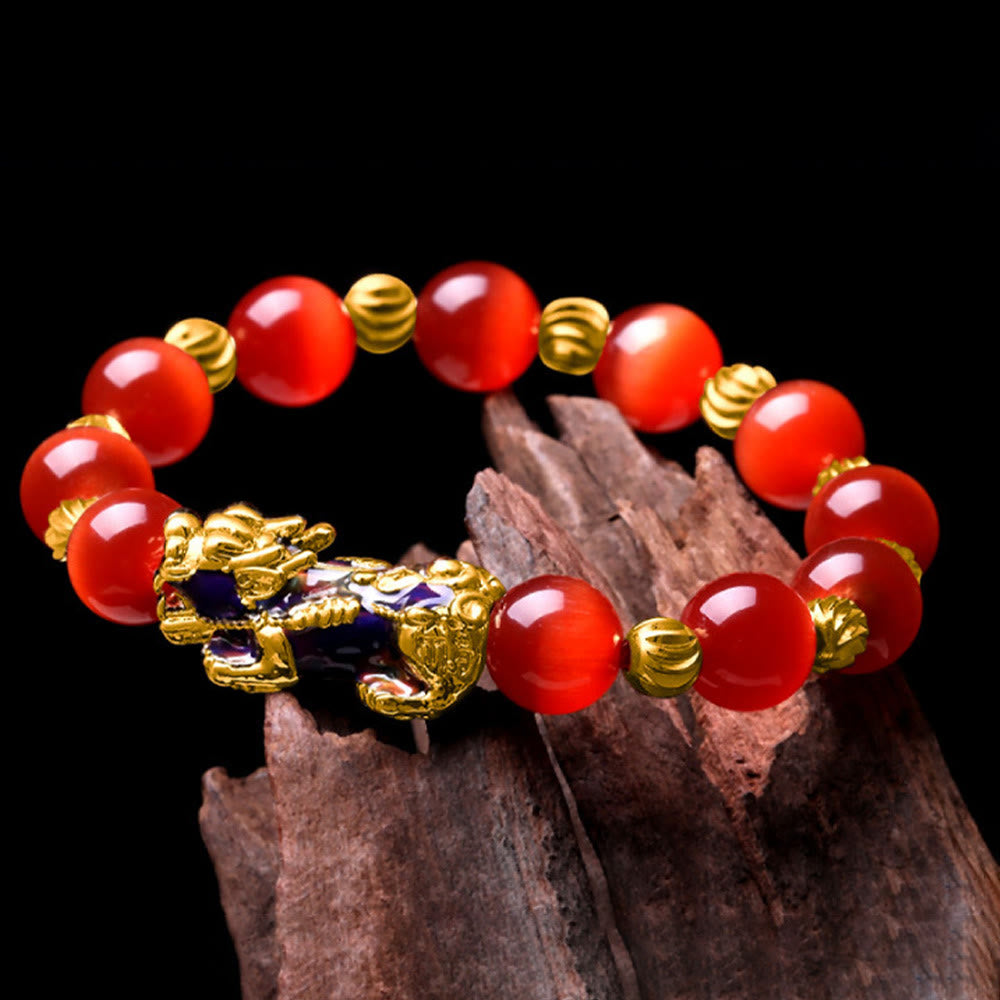 Red cat's eye bracelet draped on dark wood against black background