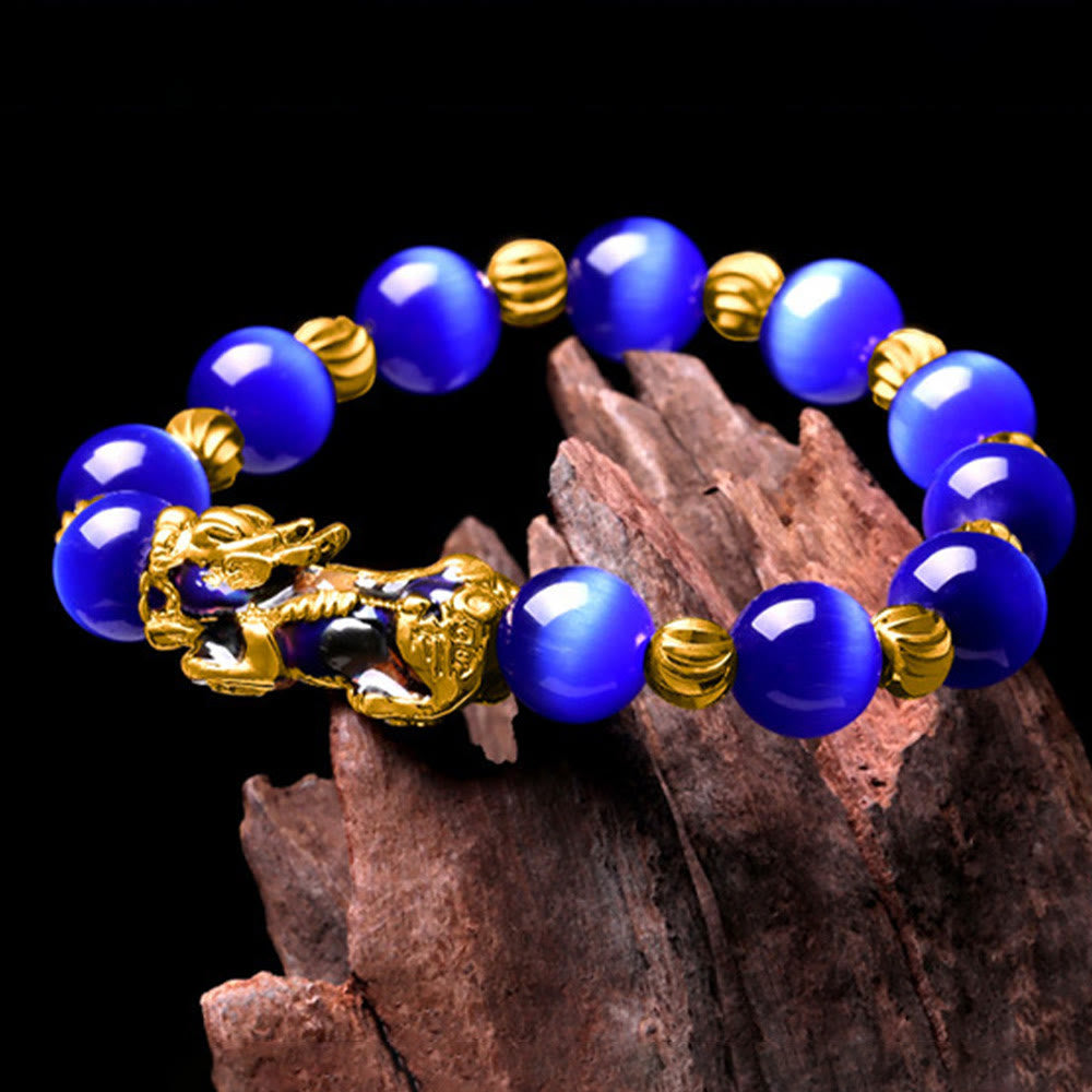 Blue cat's eye bracelet draped on dark wood against black background