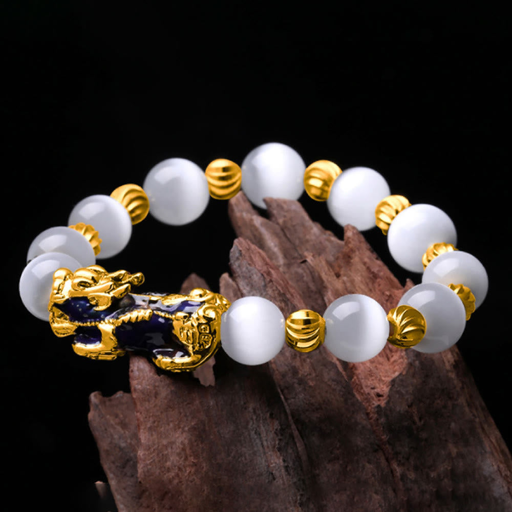 White cat's eye bracelet draped on dark wood against black background