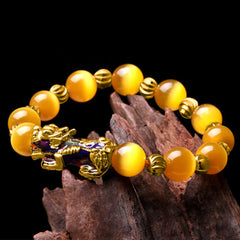 Yellow cat's eye bracelet draped on dark wood against black background