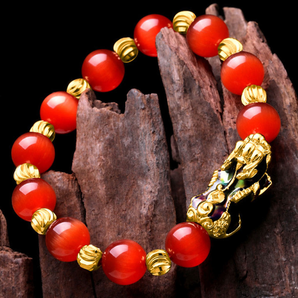 Red cat's eye bracelet on dark wood, angled overhead view