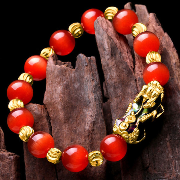 Red cat's eye bracelet on dark wood, angled overhead view