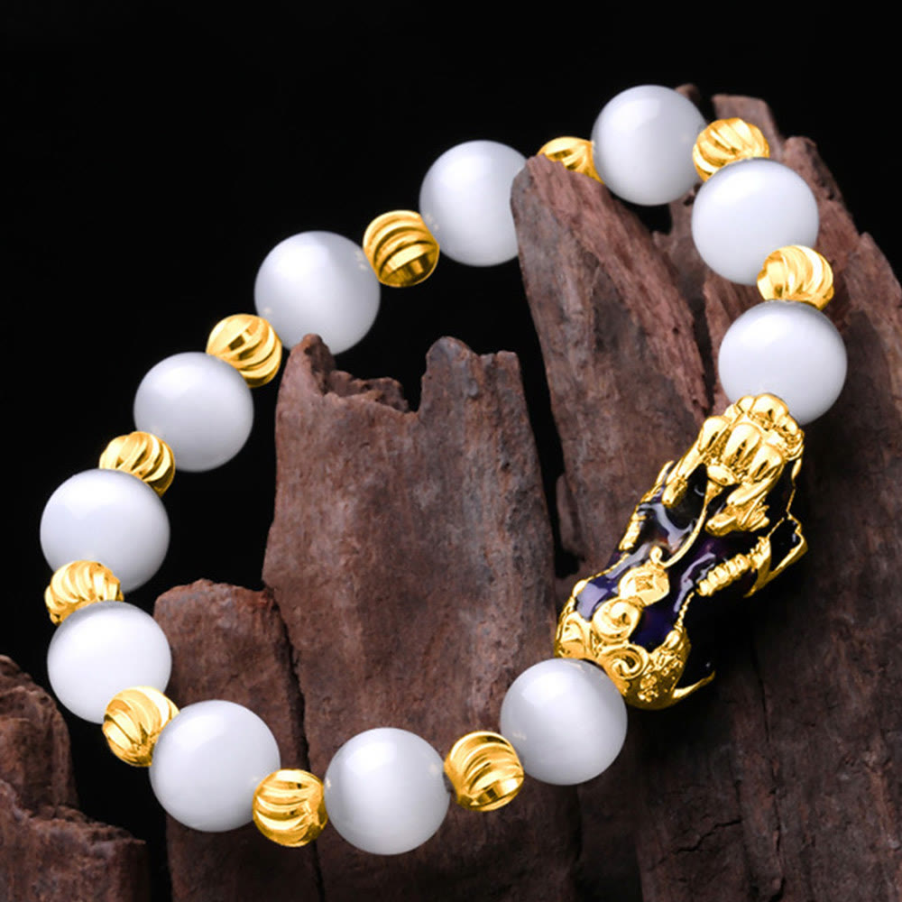 White cat's eye bracelet on dark wood, angled overhead view