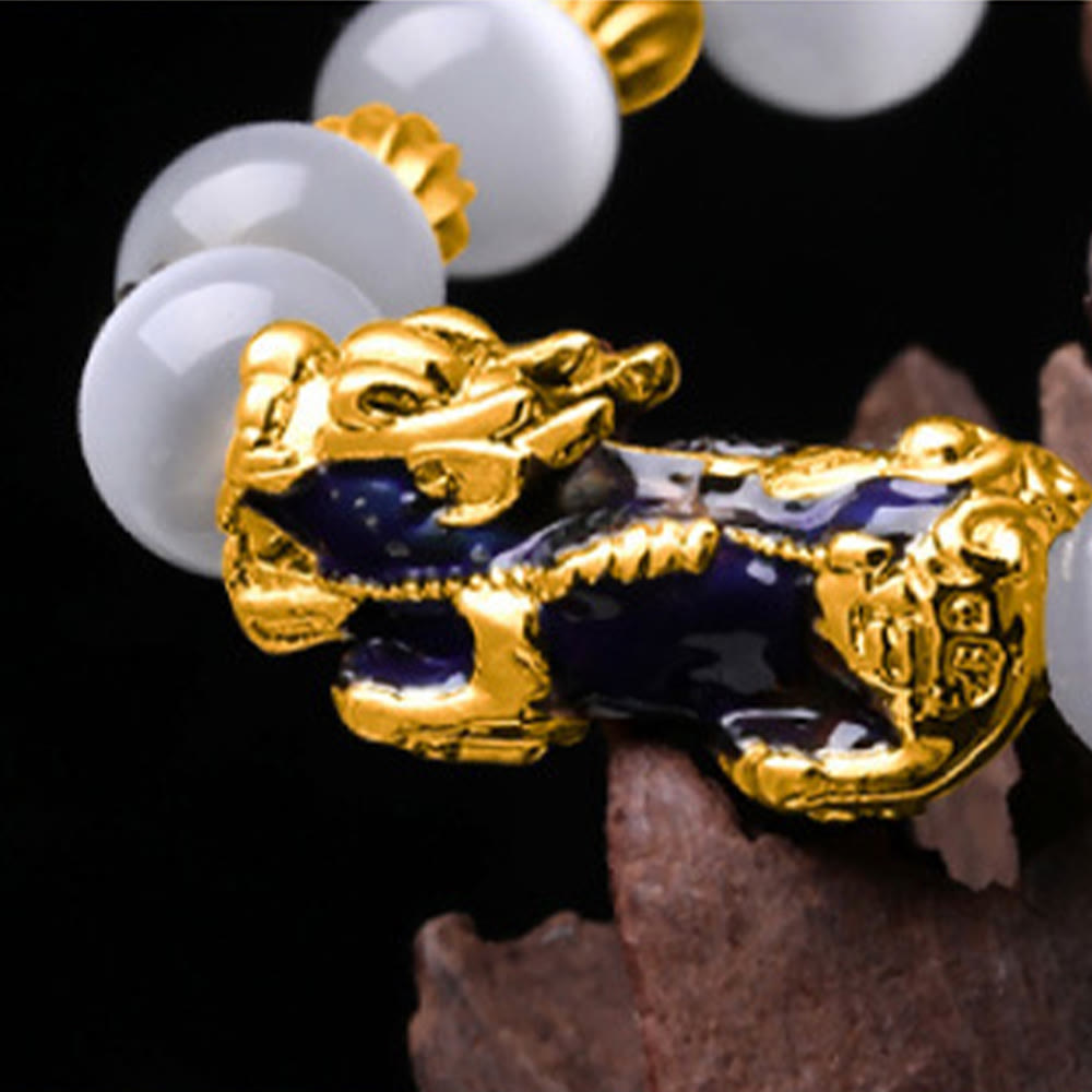 Close-up of gold and purple enamel PiXiu charm on white bead bracelet