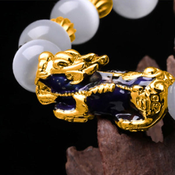 Close-up of gold and purple enamel PiXiu charm on white bead bracelet
