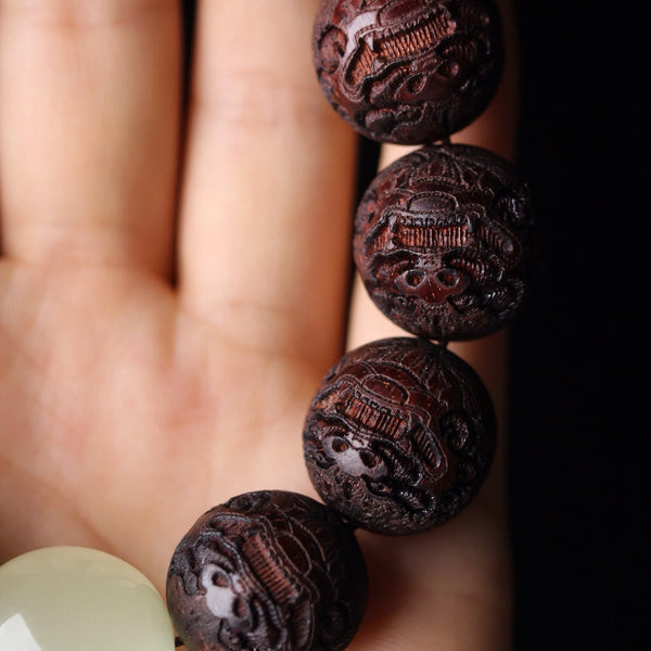 Tibetan Rosewood Engraved Pixiu Warmth Healing Bracelet – carved Pixiu beads on palm side angle macro, protection good fortune