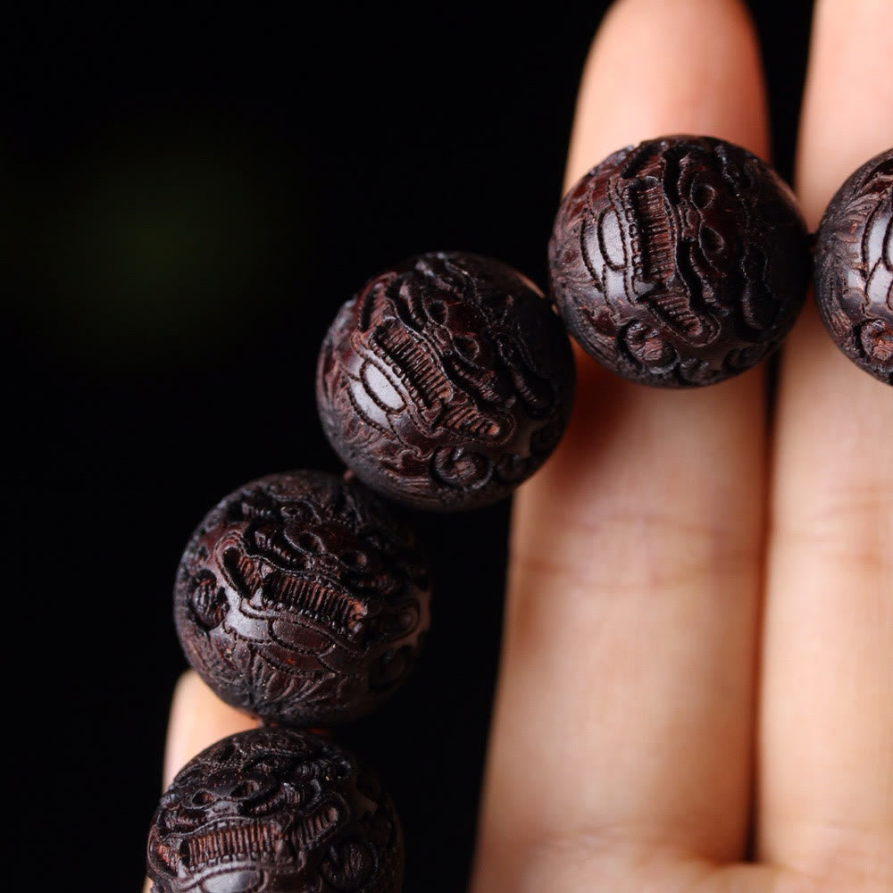 Tibetan Rosewood Engraved Pixiu Warmth Healing Bracelet – close-up three carved beads on fingers, handmade healing accessory