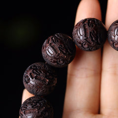 Tibetan Rosewood Engraved Pixiu Warmth Healing Bracelet – close-up three carved beads on fingers, handmade healing accessory