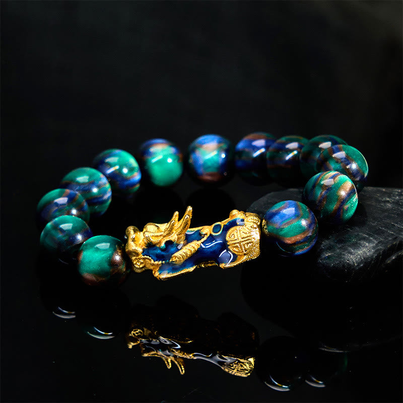 Green-blue sea willow bracelet with gold PiXiu on reflective black surface
