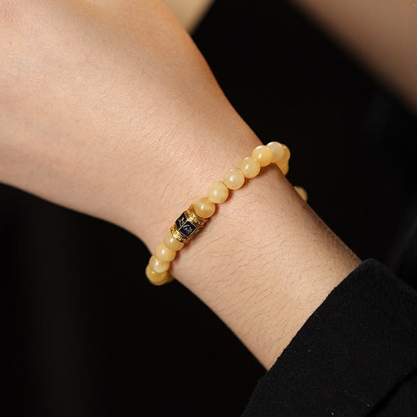 Om Mani Padme Hum Bracelet – Worn on wrist against black clothing showing warm topaz tones, bead jewelry