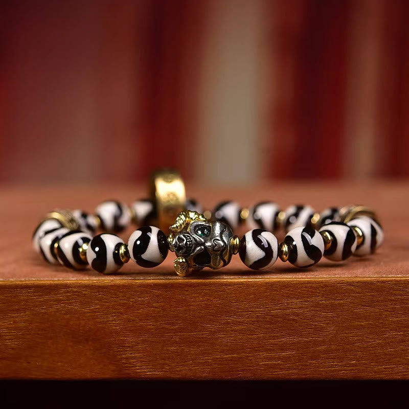 Tibetan Dzi Bead & Copper Om Mani Padme Hum Bracelet – Low angle close-up of guardian deity focal bead with green stone eyes, spiritual jewelry