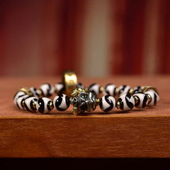 Tibetan Dzi Bead & Copper Om Mani Padme Hum Bracelet – Low angle close-up of guardian deity focal bead with green stone eyes, spiritual jewelry