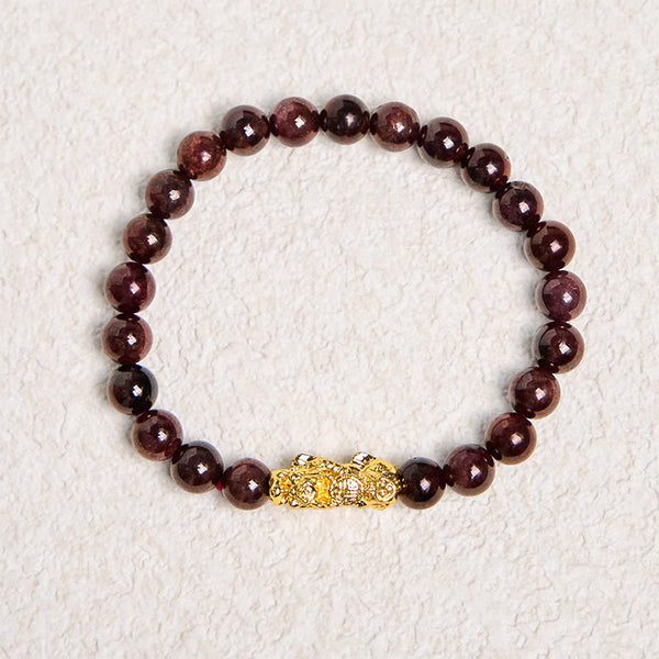 Natural Garnet Pixiu Protection Bracelet – full circle view on textured white background, dark red garnet beads with gold Pixiu charm, wealth luck