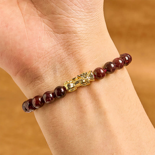 Natural Garnet Pixiu Protection Bracelet – wrist view showing single strand dark garnet beads with gold Pixiu charm, protection luck elastic