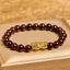 Natural Garnet Pixiu Protection Bracelet – front view on gold box showing dark red garnet beads with large gold Pixiu charm center, feng shui wealth