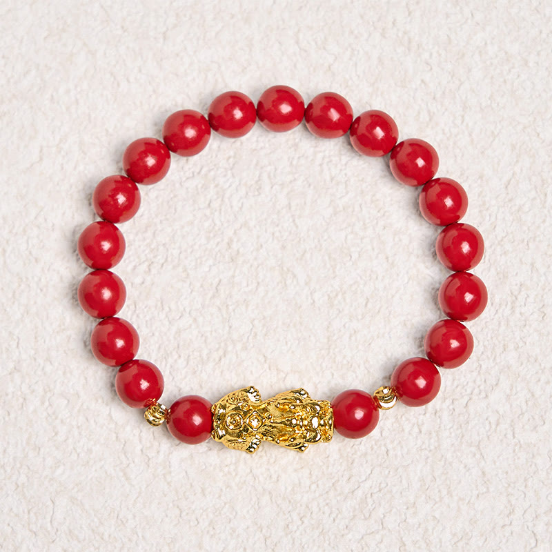 Cinnabar Pixiu Calm Bracelet – full circle view on textured white background, red cinnabar beads with gold Pixiu charm, calm protection