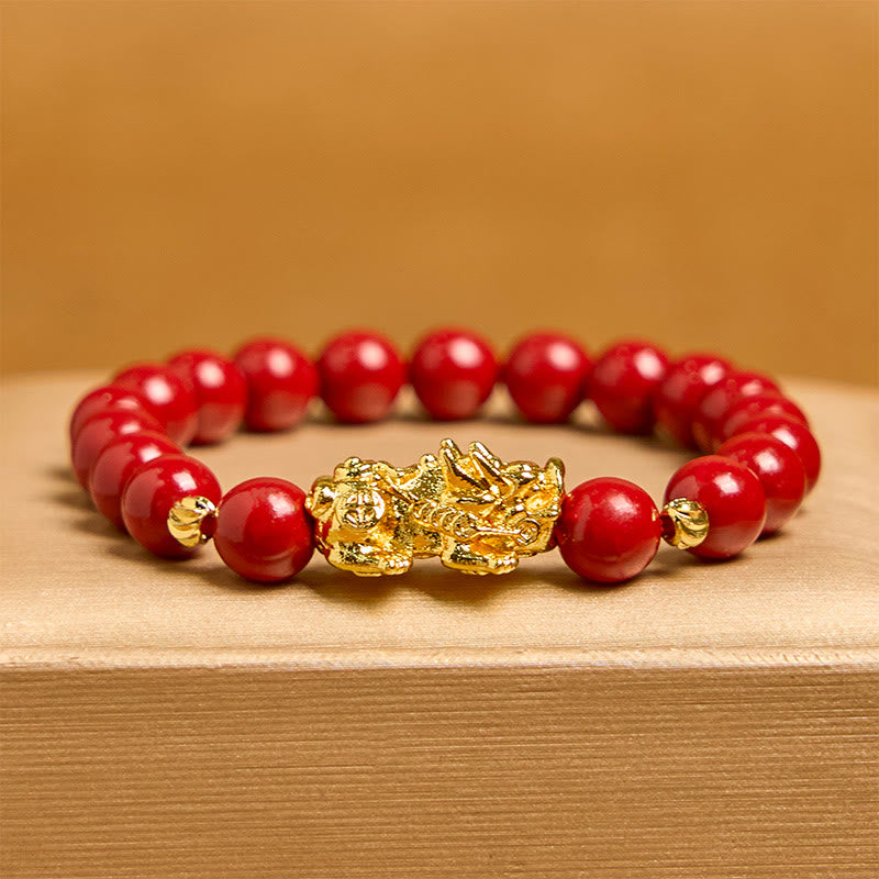 Cinnabar Pixiu Calm Bracelet – front view with amber background, single strand red cinnabar beads with ornate gold Pixiu centerpiece, luck