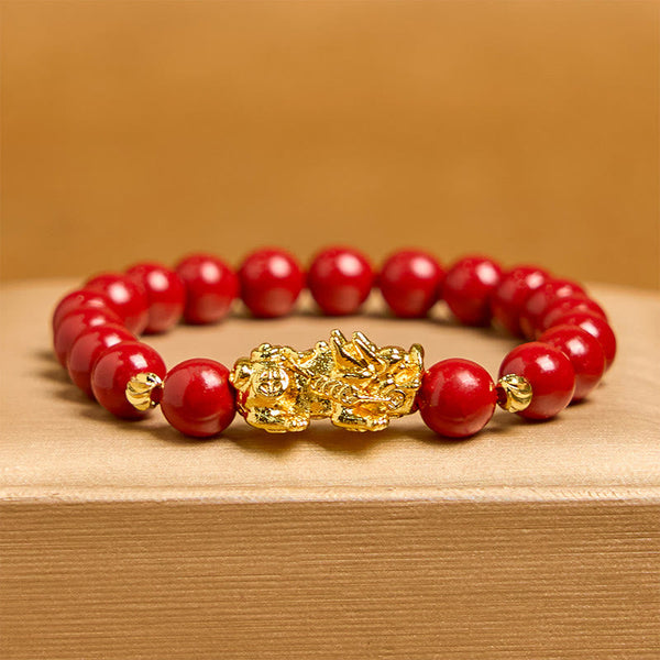 Cinnabar Pixiu Calm Bracelet – front view with amber background, single strand red cinnabar beads with ornate gold Pixiu centerpiece, luck