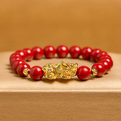 Cinnabar Pixiu Calm Bracelet – front view with amber background, single strand red cinnabar beads with ornate gold Pixiu centerpiece, luck