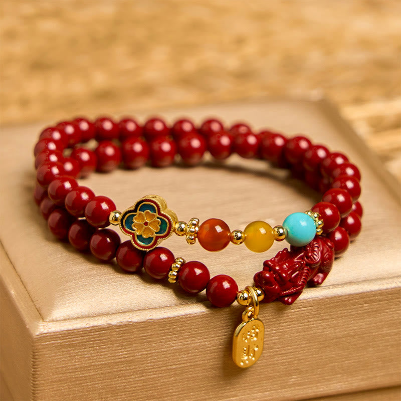 Cinnabar Pixiu Fu Bracelet – front view on gold box showing double wrap red cinnabar beads with enamel flower and Pixiu charm, feng shui