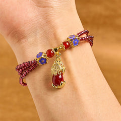 Garnet Pixiu Flower Bracelet – wrist view showing triple strand garnet with blue enamel flowers and gold Pixiu pendant, feng shui wealth charm