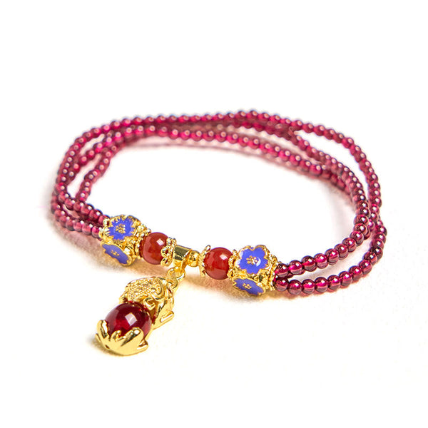 Garnet Pixiu Flower Bracelet – clean product shot on white background showing triple strand garnet beads with blue flowers and gold Pixiu, luck